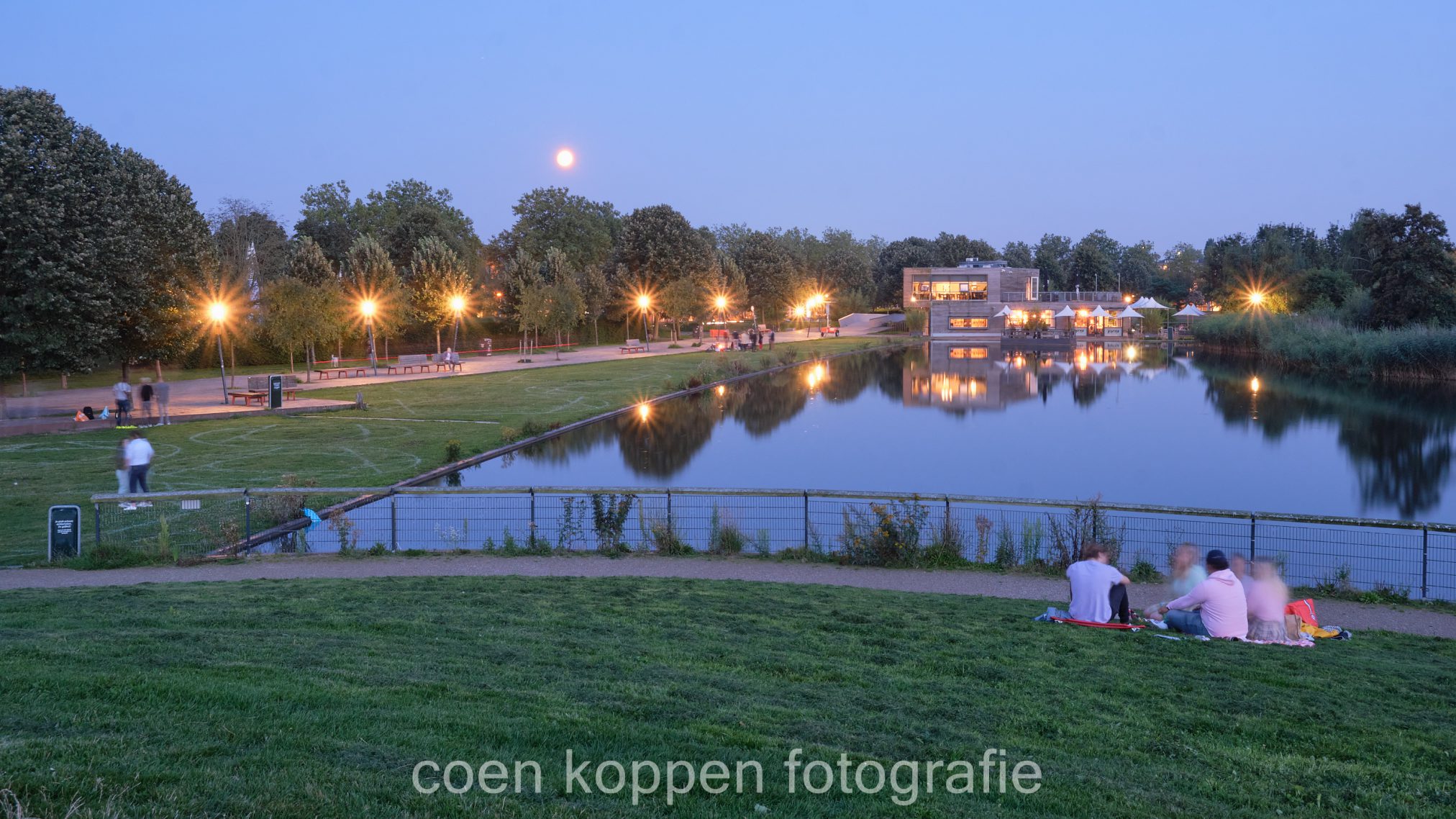 Mensen genieten in het Griftpark tijdens het blauwe uurtje met zicht op Peter's Bistro - Coen Koppen Fotografie